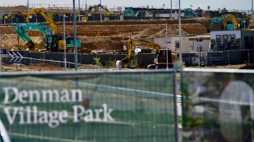 A construction site with a fence that reads "Denman Village Park".