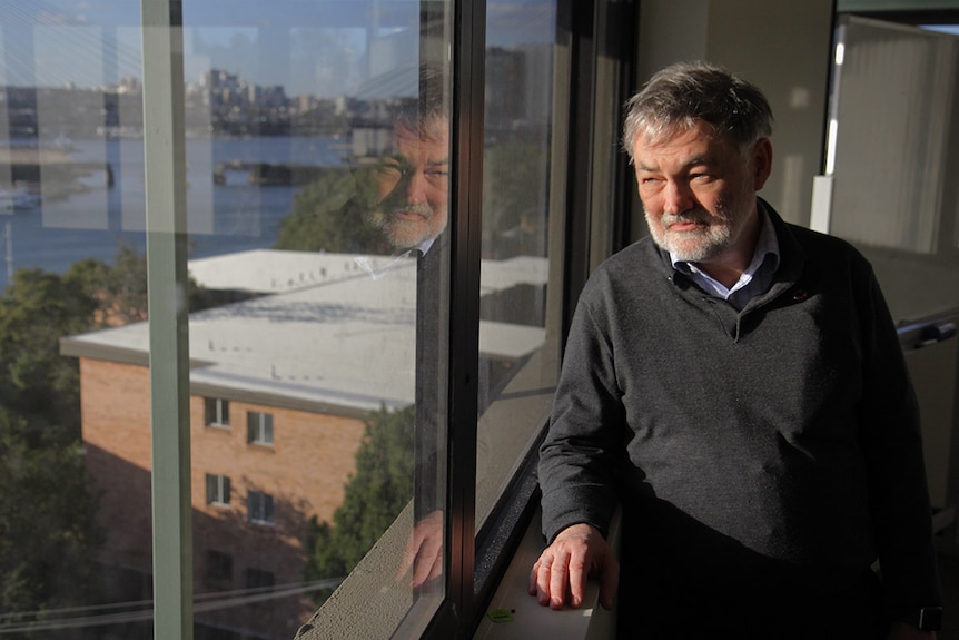 Mature aged man stands next to window