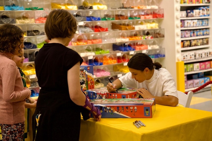 Sam Kerr signs toy boxes for fans in a shopping centre