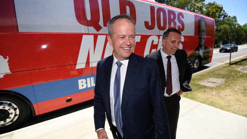 Bill shorten stands next to his campaign bus