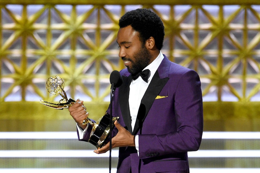 Donald Glover accepts the award, looks extremely overwhelmed, wears a purple suit.