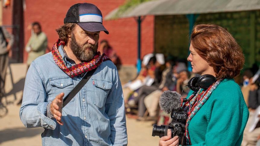 Edgerton talking to Bissland holding a camera.