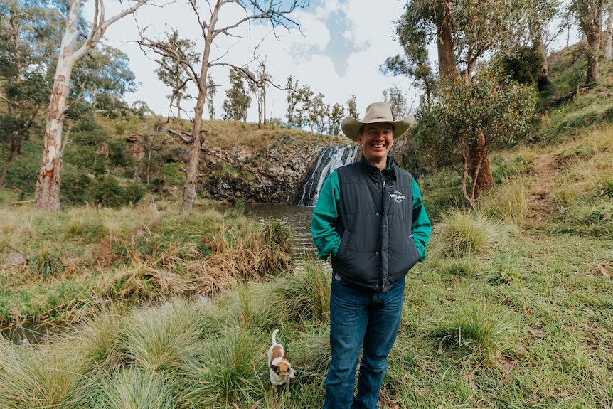 Cattle produce Stuart Austin standing on his property in front of a water fall.