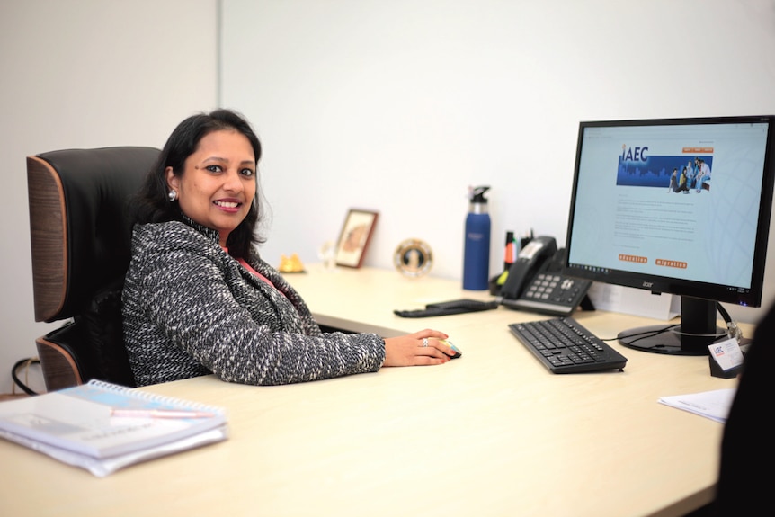 A woman seated at a desk in front of a computer screen