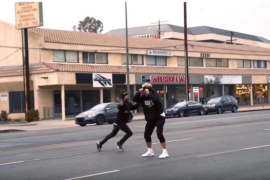 YouTuber Jake Paul stands in the middle of the road wearing a blindfold and facing oncoming traffic.