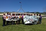 Members of women's shelter Toora Women Inc.with banners outside Parliament House.