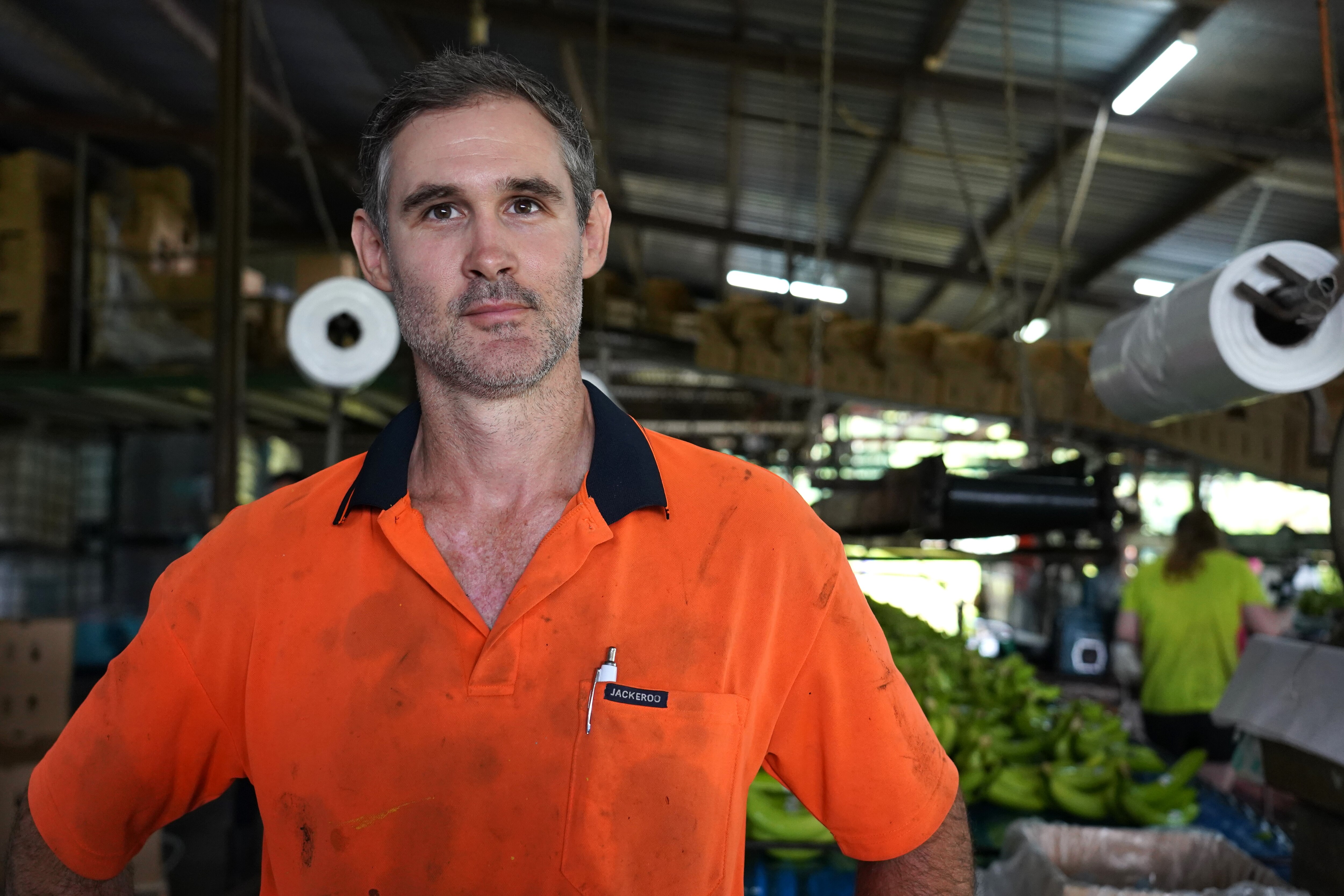 A man in high-vis stands in a shed.