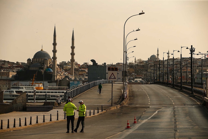 Two officers in high-vis stand in the middle of an empty three-lane highway.