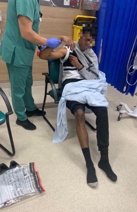 A nurse holds a boy's hand, while he sits down
