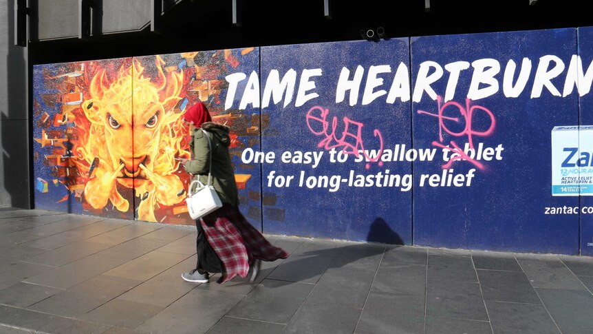 Woman walking past a Zantac advert in street art style.
