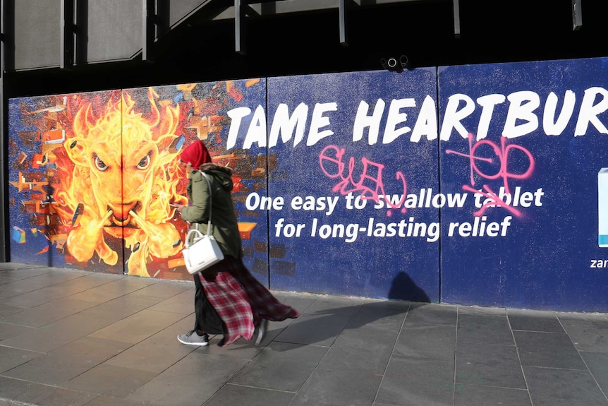 Woman walking past a Zantac advert in street art style.