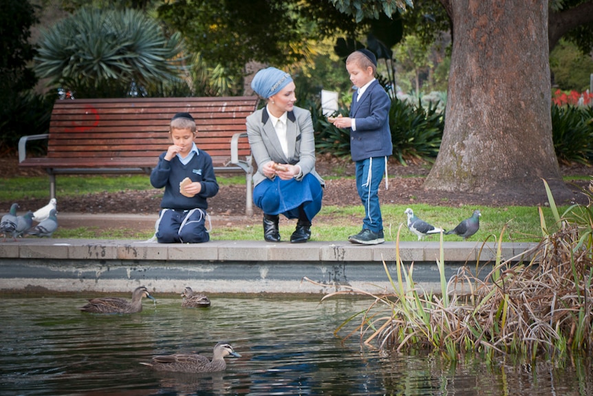 Yehudit Korkus feeding ducks with her two sons