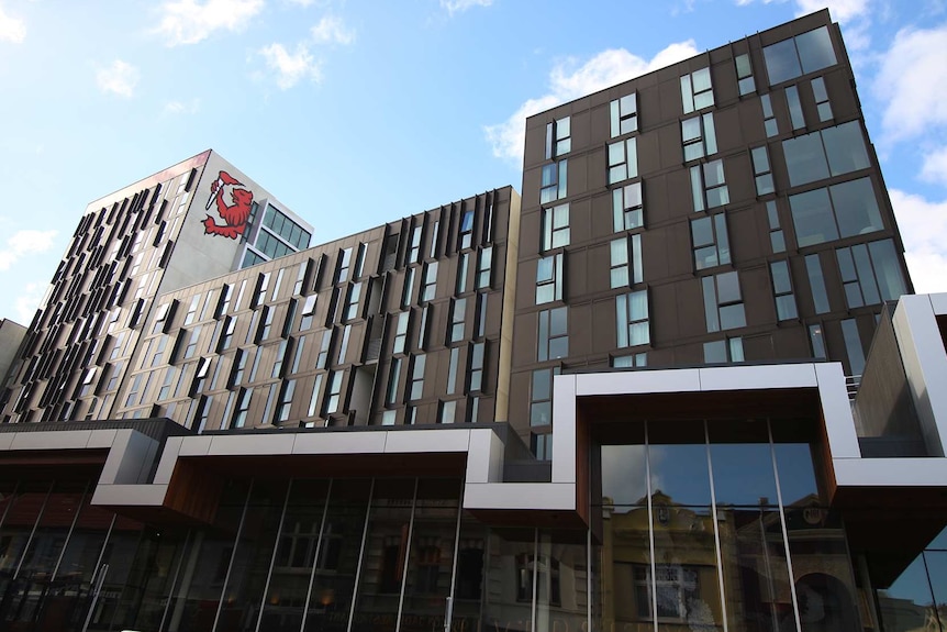 A tall building with a UTAS logo emblazoned on a high wall, photographed from street level.