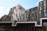A tall building with a UTAS logo emblazoned on a high wall, photographed from street level.