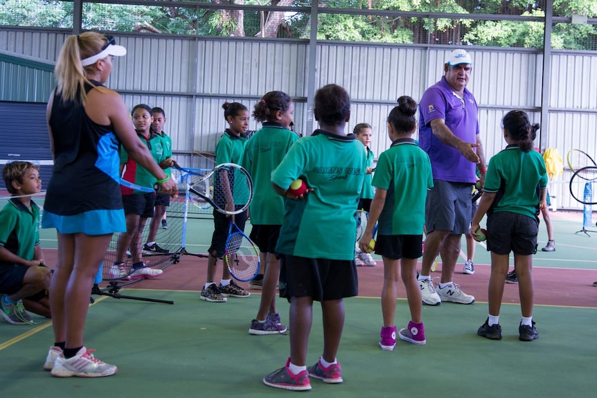 Ian Goolagong teaches students at Cairns West State School exactly how they should hold a tennis racquet.