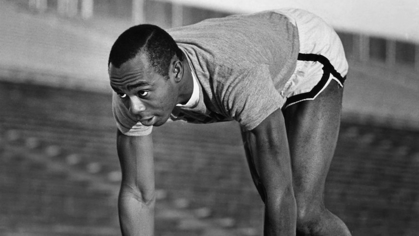 An athlete leans over, getting set to run a sprint in training.