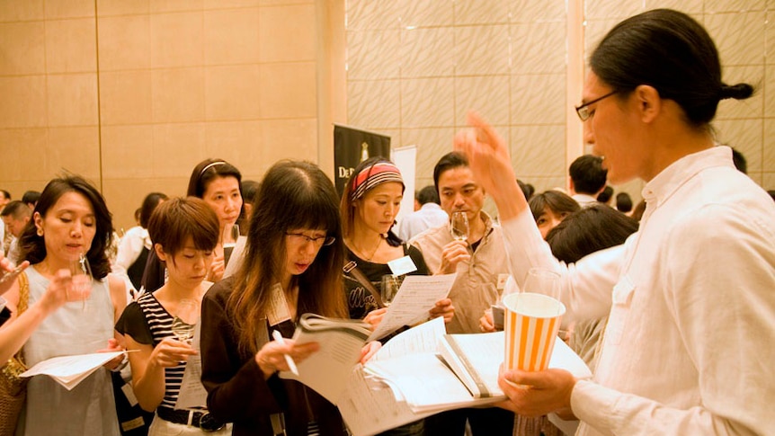 A woman stand in front of a crowded room of mostly Japanese women with note books
