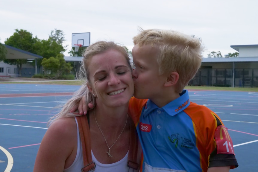 woman getting kissed on the cheek by a boy