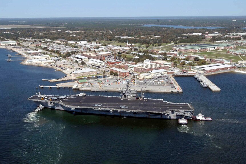 An aerial view of the Naval base in Florida, with an aircraft carrier in the foreground.