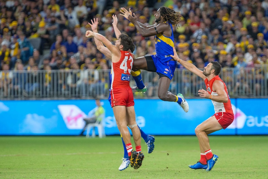 West Coast Eagles ruckman Nic Naitanui leaps for a mark sandwiched by two Sydney Swans players at Perth Stadium.