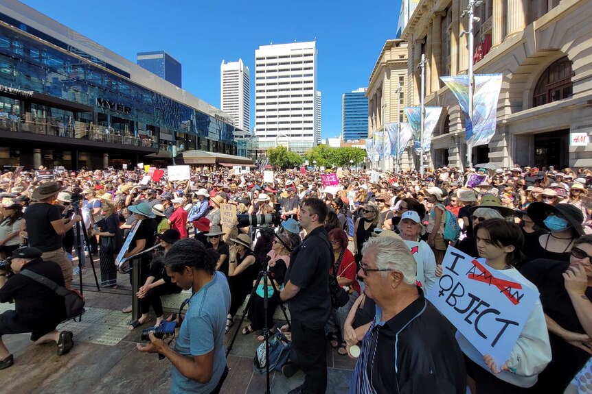 A crowd stretches to fill Forrest Place, holding signs.