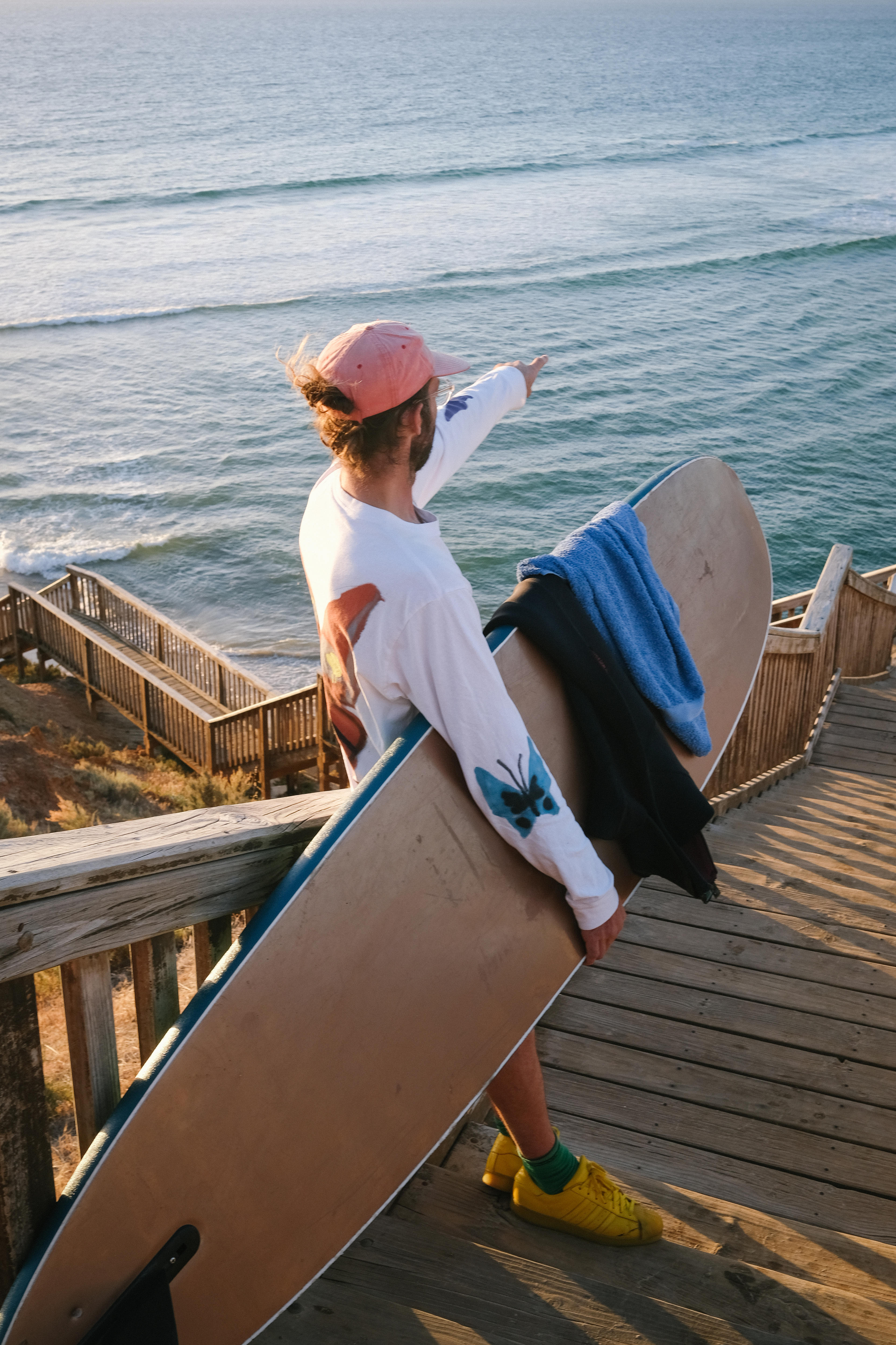 Artist Henry holds his surfboard overlooking the ocean 