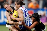 Jasmine Garner is crunched between two Richmond players in a tackle