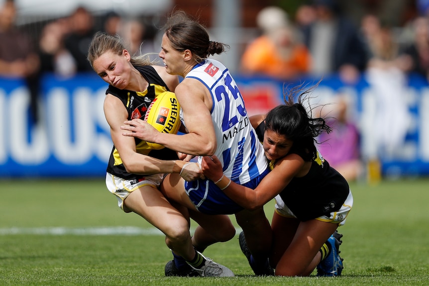 Jasmine Garner is crunched between two Richmond players in a tackle