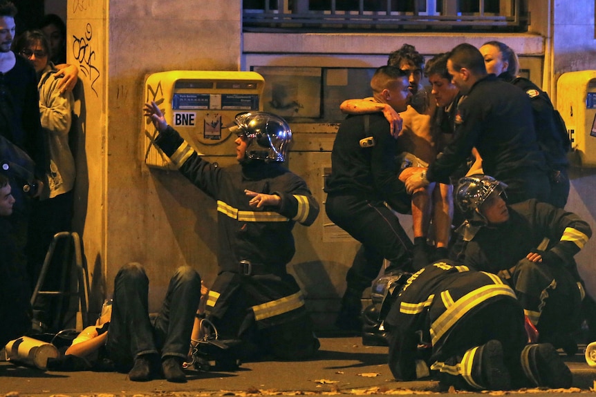 French fire brigade members aid an injured individual near the Bataclan concert hall