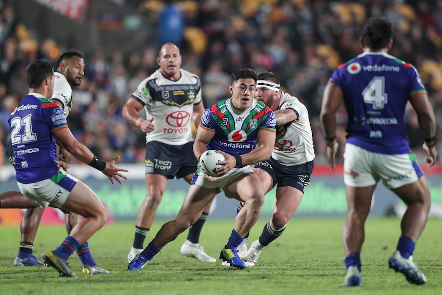 A rugby league player turns towards his team ready to pass the ball during an NRL game.