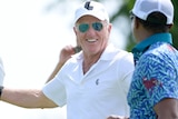 Greg Norman smiles while speaking to someone