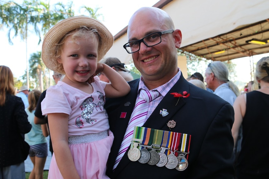 Private Aaron Jarman holding his daughter and wearing his medals