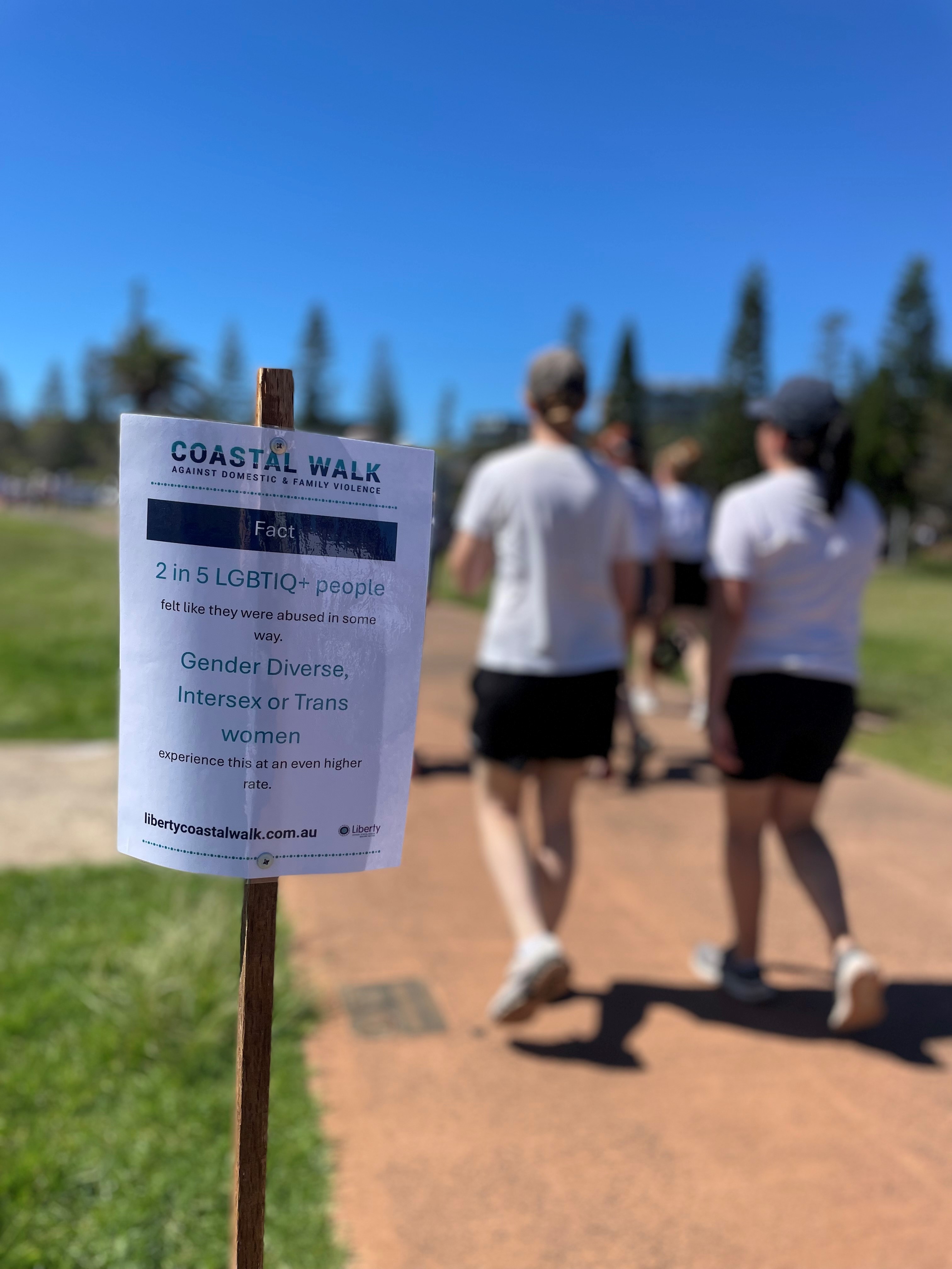A sign saying 'coastal walk against domestic violence' and showing information about violence against LGBT people.
