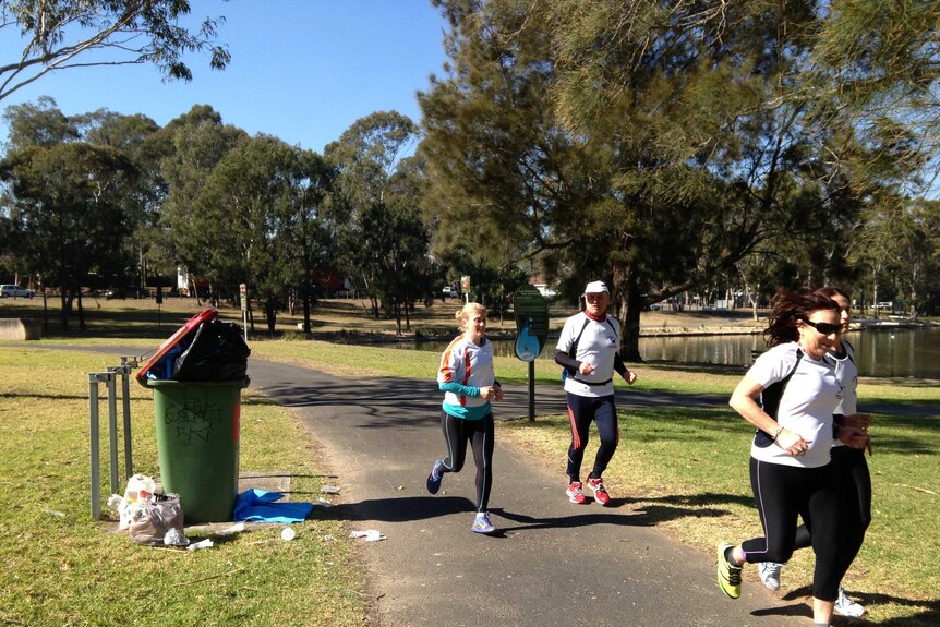 Joggers run past litter in Henry Lawson Reserve
