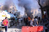 Syrian civil defence workers put out a fire as Syrian citizens gather after an air strike.