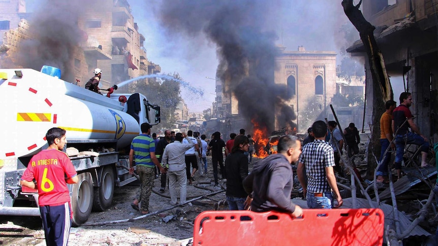 Syrian civil defence workers put out a fire as Syrian citizens gather after an air strike.