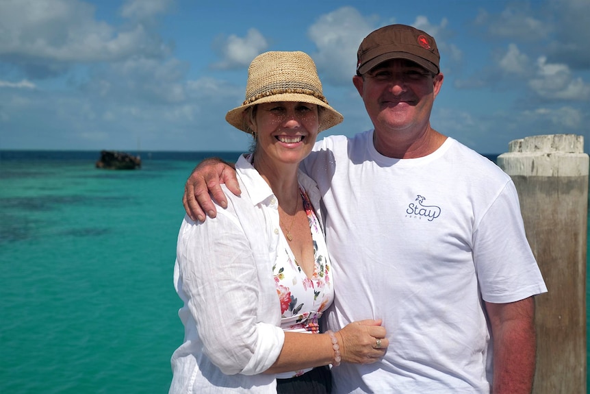 Trudi and Ben with their arms around each other smilind, ocean behind.