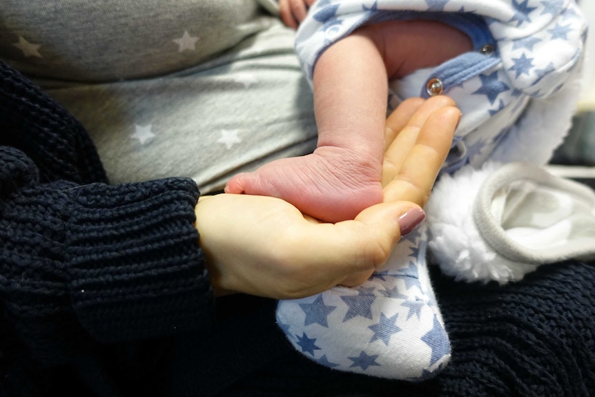 A close-up shot of a baby's foot in his mother's hand.
