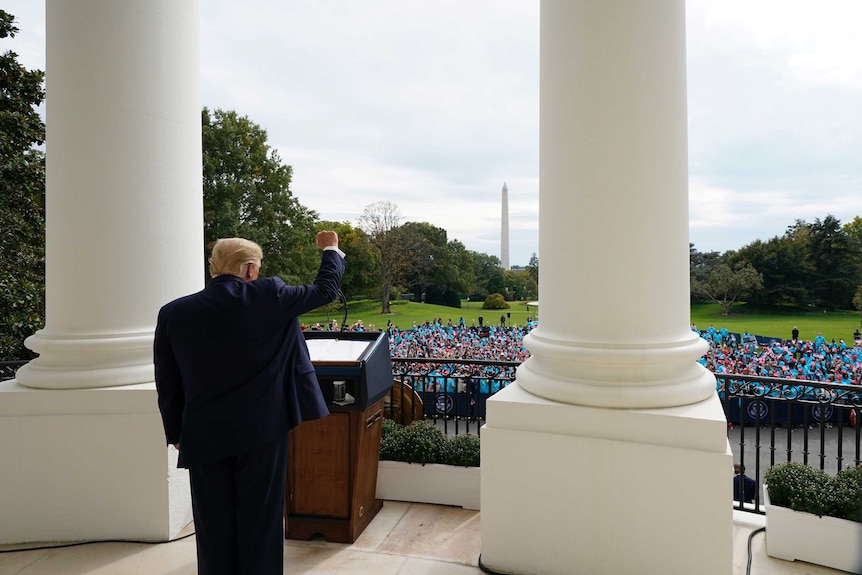 President Donald Trump gestures from the Blue Room Balcony of the White House