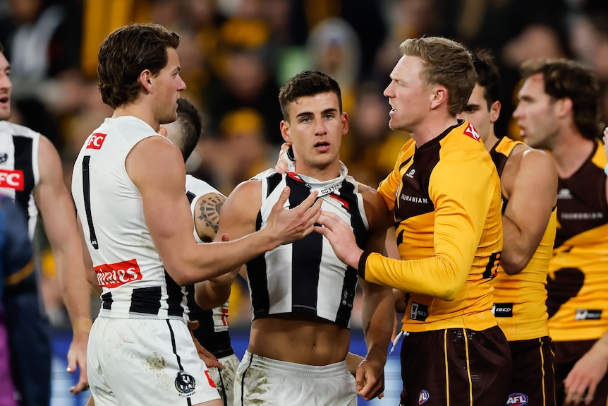 Nick Daicos looks dishevelled as Magpies and Hawks players mill around him
