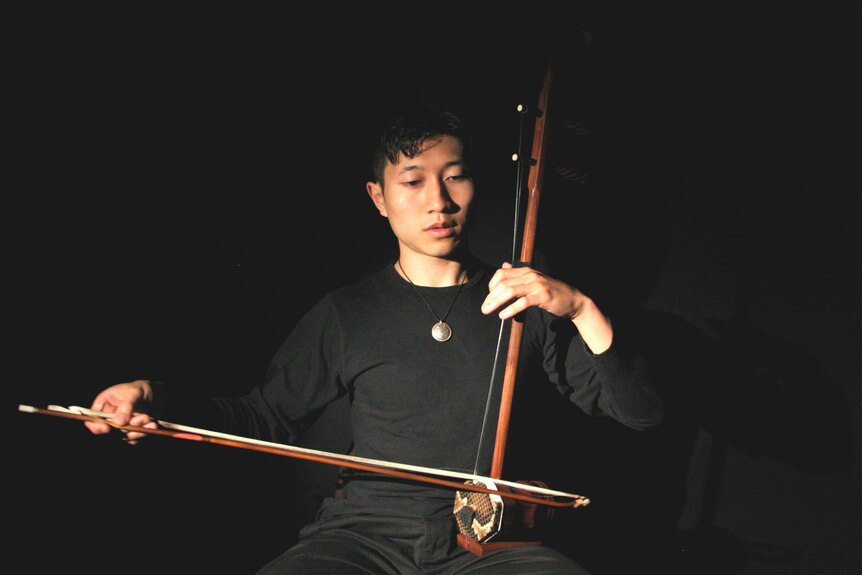 Nicholas Ng plays the Chinese bowed instrument, the Erhu. The snakeskin on the resonator box is clearly visible.. 