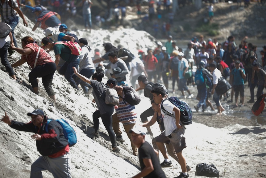 migrants carrying children walk near the bank of the Suchiate River at the border of Mexico and Guatemala