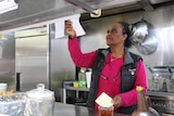 a woman at a restaurant food pass, looking at a food order