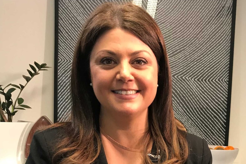 Laura Berry sits smiling in an office with her hands folded