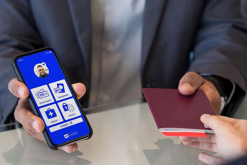 A person at a counter handing over a passport and showing a phone display 