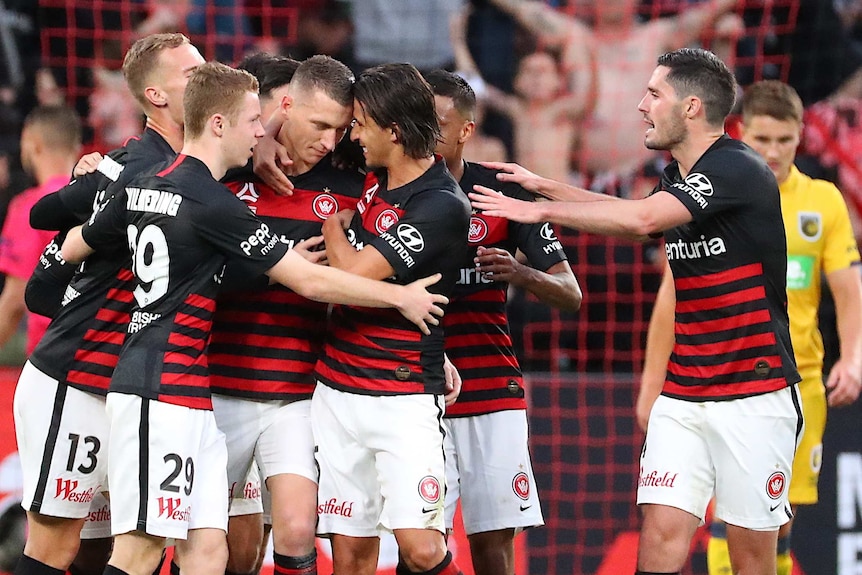 Western Sydney Wanderers players embrace as they celebrate an A-League goal against Central Coast Mariners.