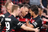 Western Sydney Wanderers players embrace as they celebrate an A-League goal against Central Coast Mariners.