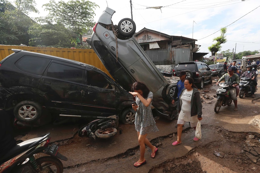 Residents walk near the wreckage of cars that were swept away by flood in Bekasi, West Java.