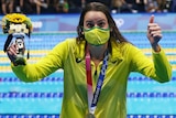 Wearing her gold medal and holding the Tokyo mascot, Kaylee McKeown gives a big thumbs up