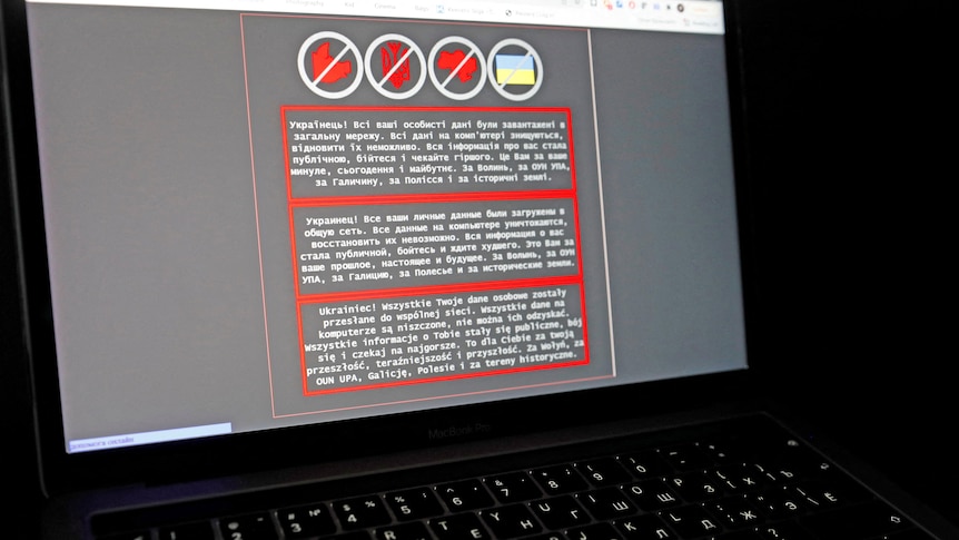 A laptop screen displays a warning message in Ukrainian, Russian and Polish